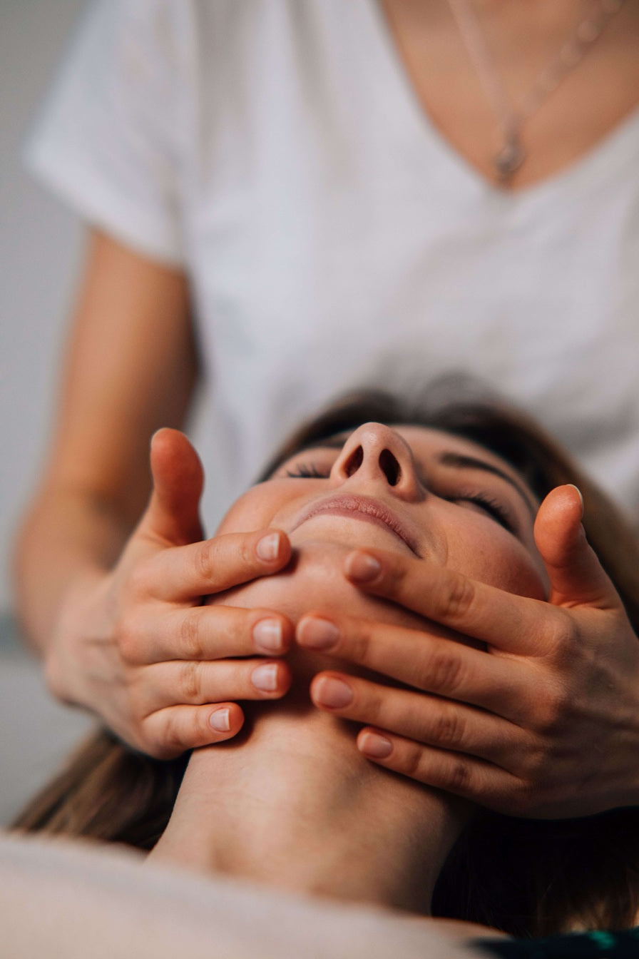 Person receiving a facial massage with hands on a blurred background